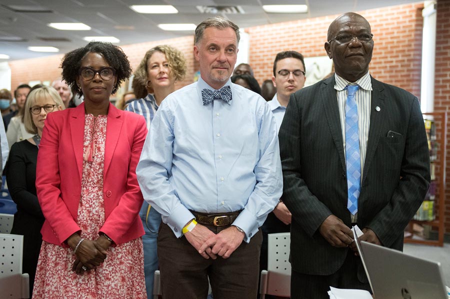 Image of audience standing. At the front is Director Colleen Russell-Rawlins, Board Chair Alexander Brown and Trustee Smith Open Gallery